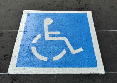 A blue and white handicap sign is painted on a sidewalk.