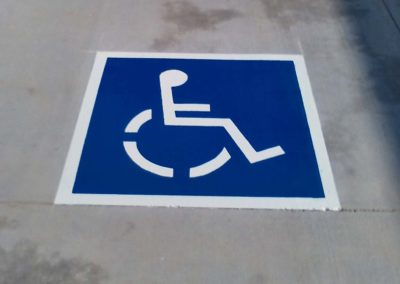 A blue and white handicap sign on a sidewalk.