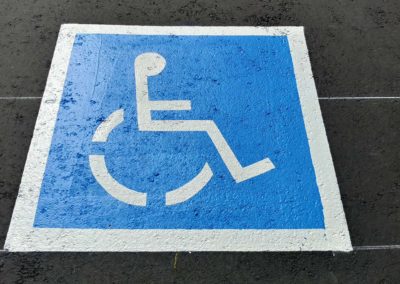 A blue and white handicap sign is painted on the ground.