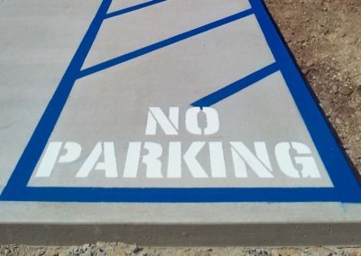 A no parking sign painted on concrete.