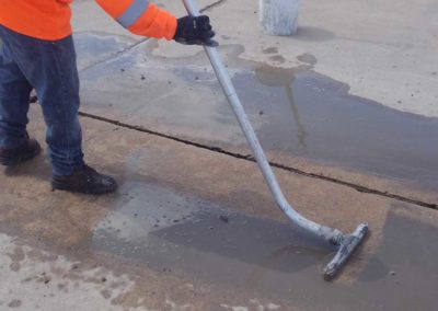 A man using a broom to clean a puddle.