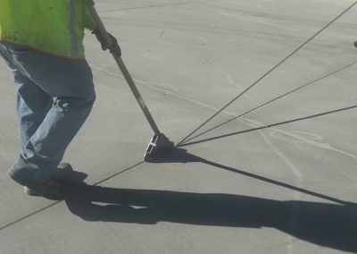 A man using a shovel to sweep a sidewalk.