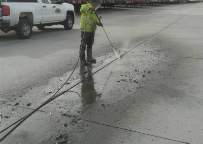 A man cleaning a parking lot with a hose.
