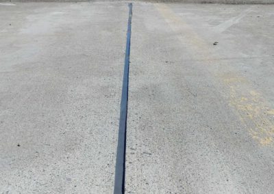 A line of black pipe in the middle of a parking lot.