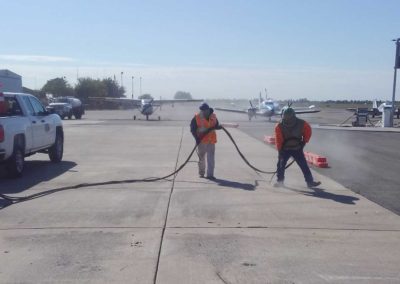 Two men with hoses working on a tarmac.