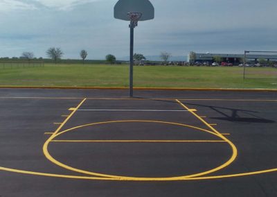 A basketball court with a yellow line and a basketball hoop.