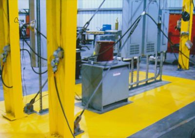 A yellow floor in a factory with a lot of equipment.
