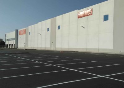 A large warehouse with a parking lot in front of it.