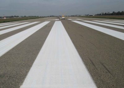 An airport runway with white lines painted on it.