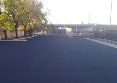 A black parking lot with a fence in the background.