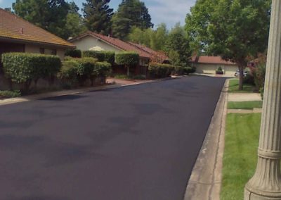 A black paved street in a residential neighborhood.