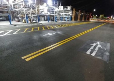 A parking lot at night with arrows painted on it.